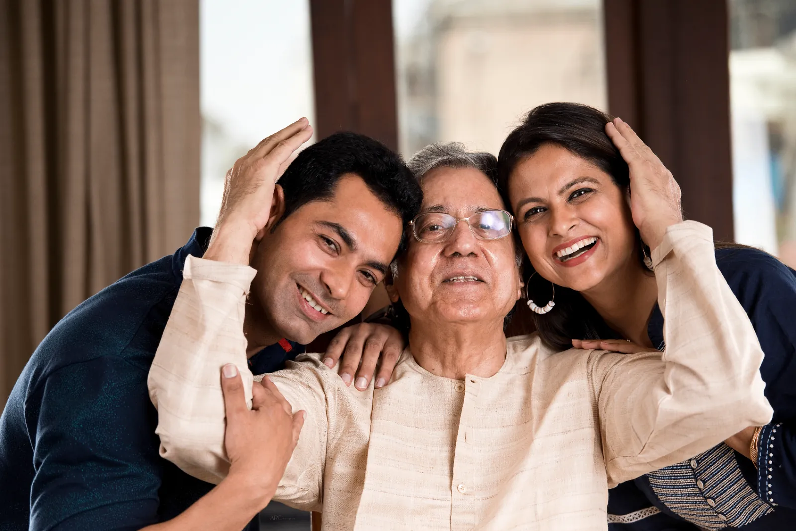 Adult children embracing their elderly father at home, illustrating Support at Home