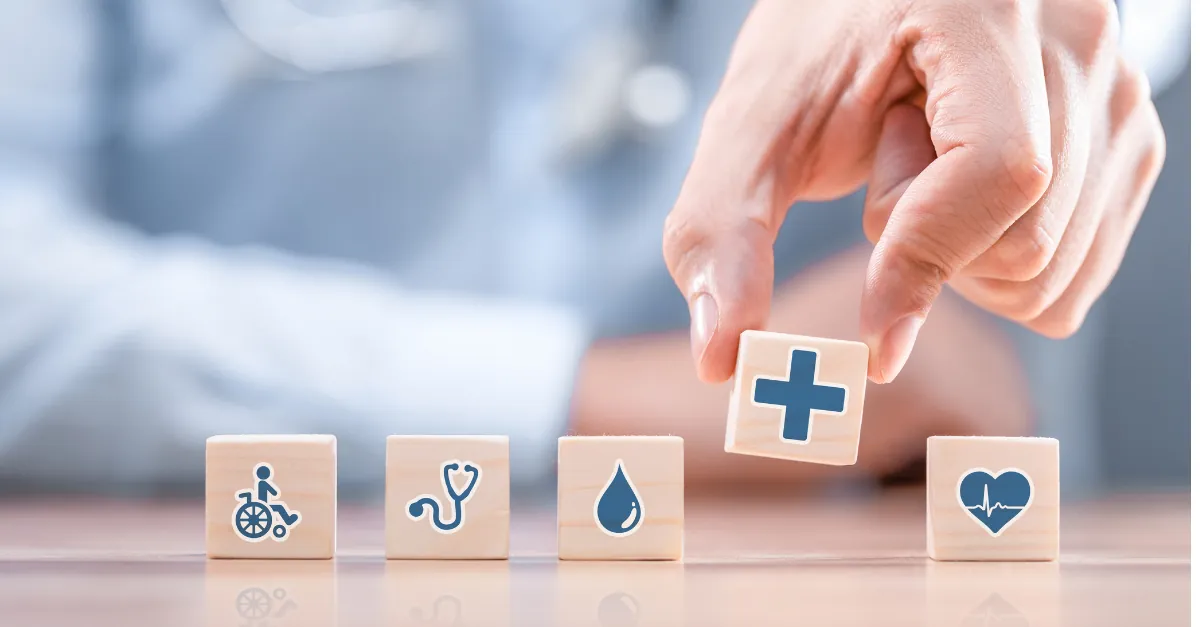 Hand placing a wooden medical cross block among other care-related blocks